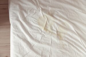 Image of pee's child on the white bed sheet. Cause stains and dirty on the mattress.